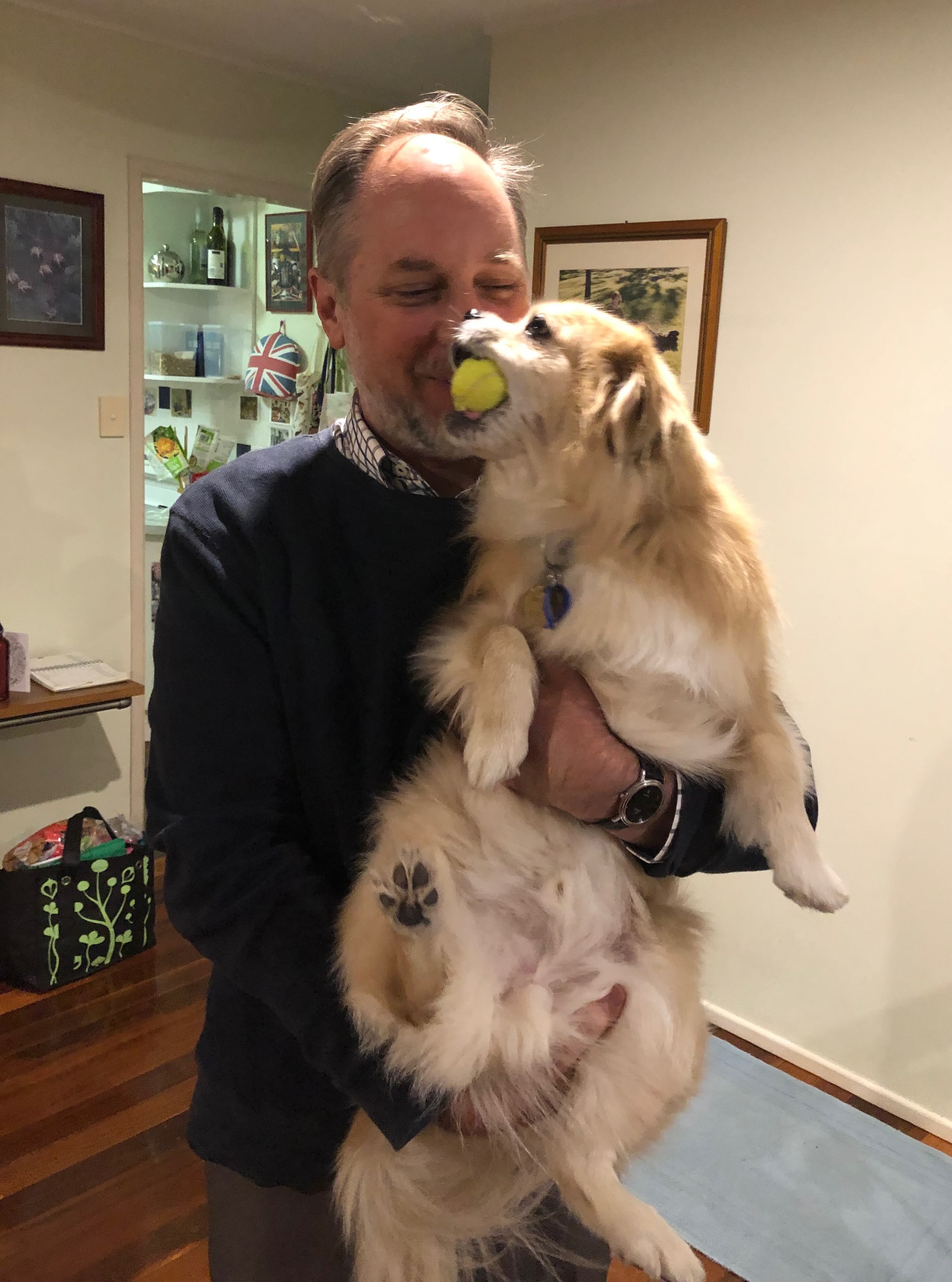 Owner holding dog with ball in its mouth